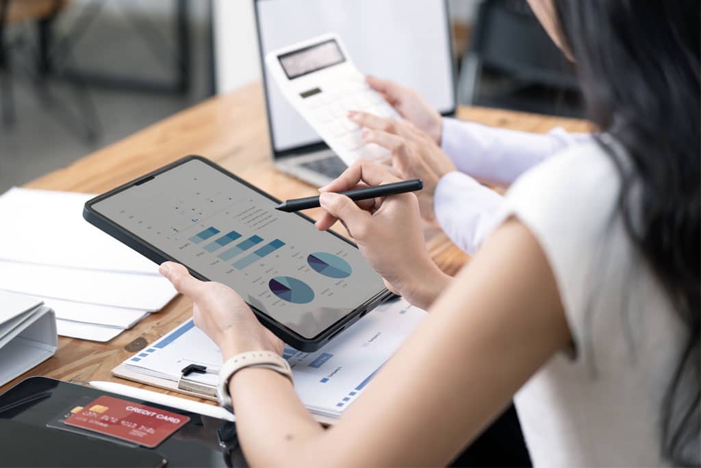 Article campagne social ads - Une femme de dos assis à un bureau et  tenant une tablette affichant des statistiques et graphiques