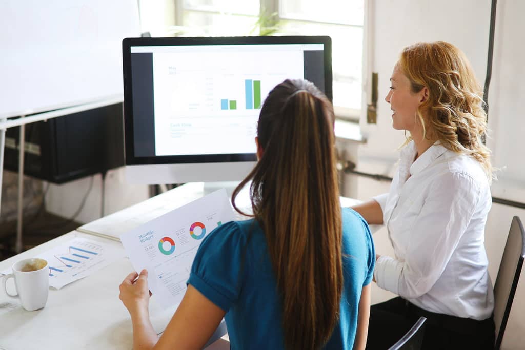 Article carrousel sur facebook - Deux femmes analysnt des graphiques sur un écran d'ordinateur et sur papier