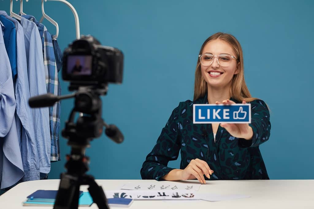 Article comment faire un live sur facebook - Une femme incitant son audience à donner des "likes"