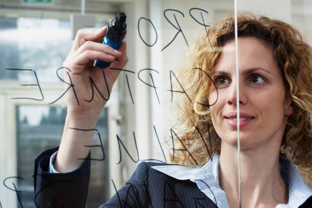 Article idées noms instagram - Une femme écrivant au feutre sur une vitre transparente