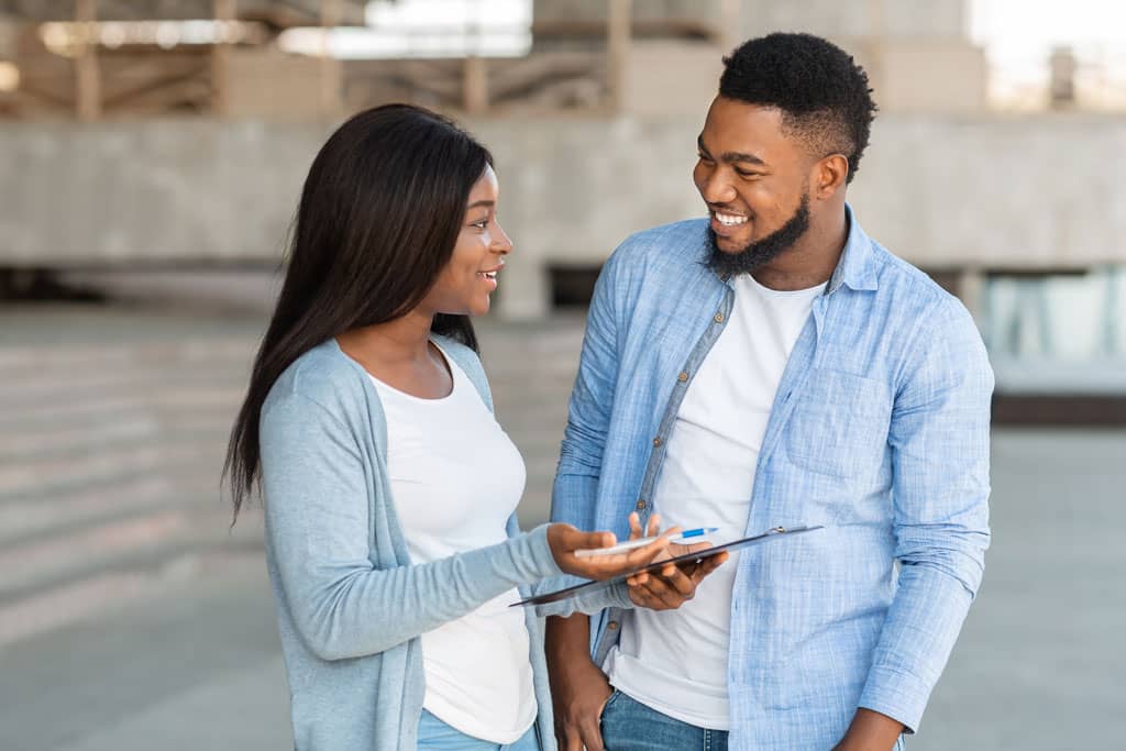 Article idées noms instagram - Deux personnes debout dans la rue discutant avec un formulaire